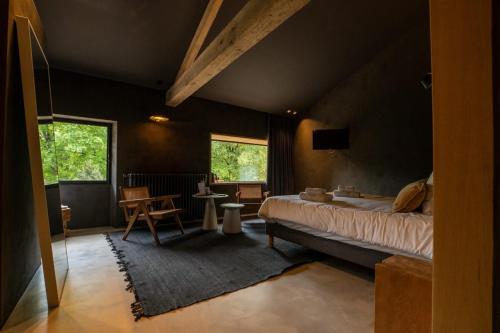 ein Schlafzimmer mit einem Bett, einem Tisch und zwei Fenstern in der Unterkunft La Maison des Sources in Angoulême