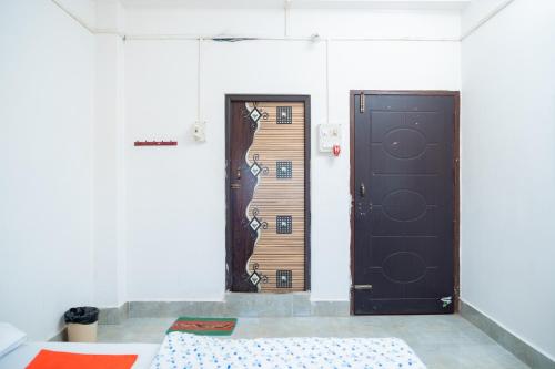 two doors in a room with a bed in front at JRB RESIDENCY in Dibrugarh