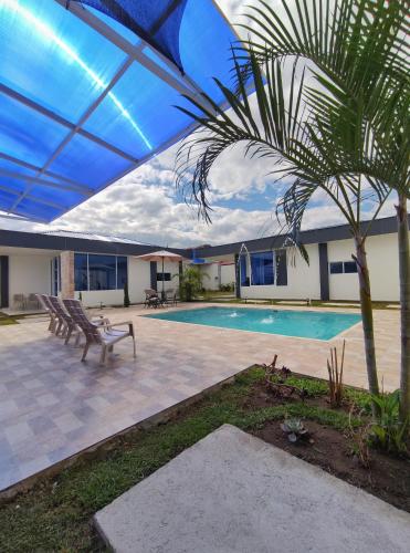 a patio with a swimming pool and a palm tree at Cabañas Compostela gigante in Gigante
