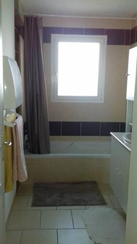 une salle de bain avec une baignoire et une fenêtre dans l'établissement Charmante maison, à Sainte-Blandine