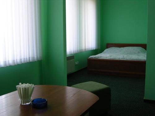 a green room with a table and a bed at Skaistažiedė in Šiauliai