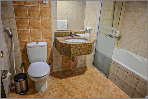 a bathroom with a toilet and a sink and a tub at فندق ديار الهدى in Al Madinah