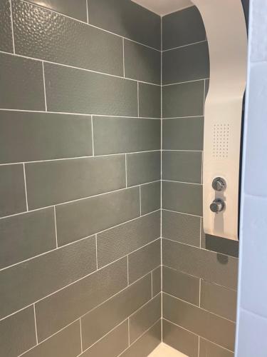 a bathroom with a shower with gray tiles at Maison rénovée au calme in Biéville-Beuville