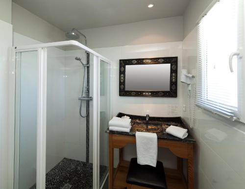 a bathroom with a shower and a sink and a mirror at Hotel St Joseph in Algajola