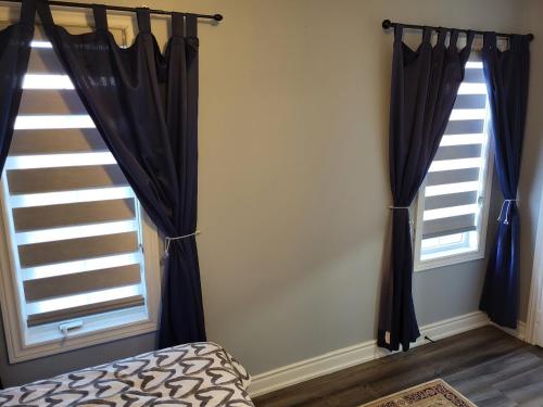 a bedroom with two windows with black curtains at Luxury Home in Mississauga in Mississauga