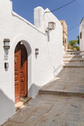 a white building with a wooden door on a street at Villa Nouna in Líndos