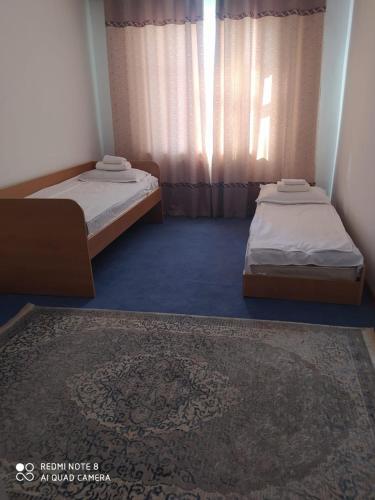 two twin beds in a room with a rug at Гостевой дом Энесай in Bishkek
