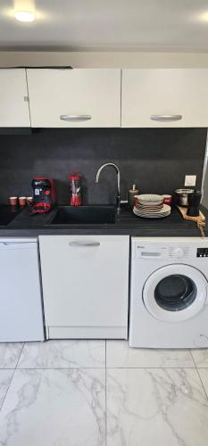une cuisine blanche avec un évier et une machine à laver dans l'établissement calme appartement de vacances, à Écouen