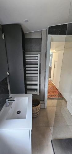 une cuisine avec un évier blanc et un couloir dans l'établissement calme appartement de vacances, à Écouen