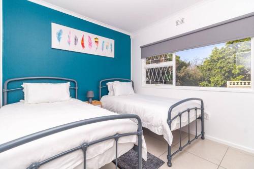 Duas camas num quarto com uma parede azul em Haus at Chappies em Noordhoek