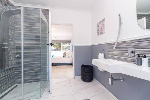 a bathroom with a glass shower and a sink at Haus at Chappies in Noordhoek