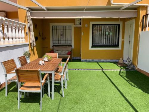 Apartamento Terraza Arenales del Sol في آريناليس ديل سول: طاولة وكراسي على فناء مع عشب أخضر