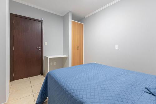 een slaapkamer met een blauw bed en een houten deur bij Ideal para Casais, Loft na Praia de Bombinhas - 1 dorm in Bombinhas