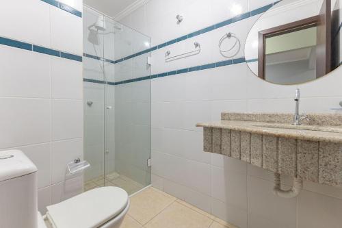 een badkamer met een toilet, een wastafel en een spiegel bij Ideal para Casais, Loft na Praia de Bombinhas - 1 dorm in Bombinhas