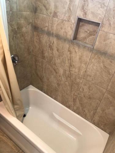 a bathroom with a shower with a white tub at Star Motel in Norwalk