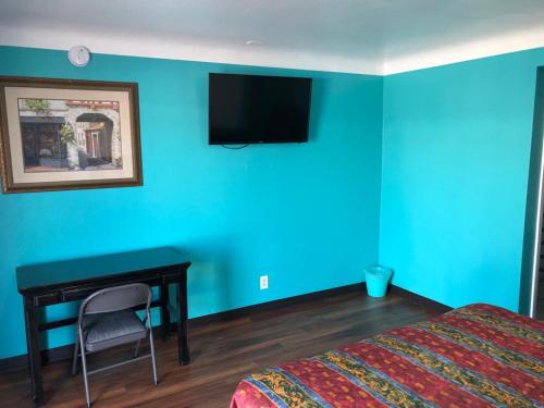 a bedroom with a blue wall with a bed and a desk at Star Motel in Norwalk