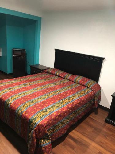 a bedroom with a bed with a colorful comforter at Star Motel in Norwalk