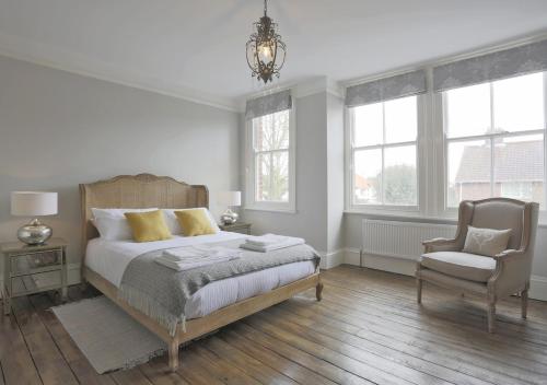 a bedroom with a bed and a chair and windows at Bay House in Southwold