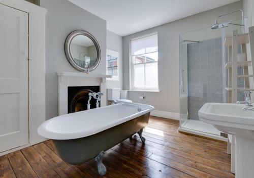 a bathroom with a tub and a sink and a mirror at Bay House in Southwold