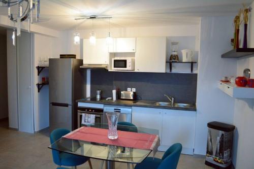 une cuisine avec une table en verre et des chaises bleues dans l'établissement Appartement charmant à la Teste de Buch, à La Teste-de-Buch