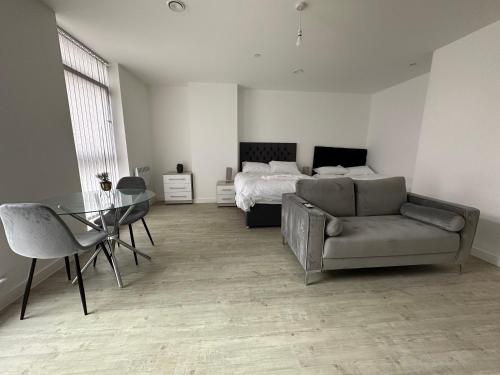 a bedroom with a bed and a couch and a table at Manchester Old Trafford Studio Apartment in Manchester