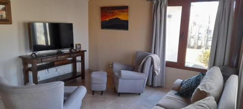 uma sala de estar com um sofá e cadeiras e uma televisão em MI CASA em El Calafate