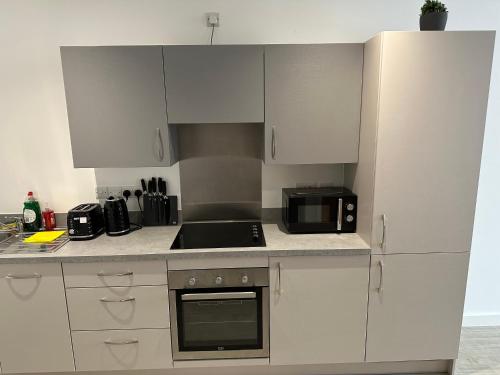 a kitchen with white cabinets and a black microwave at Manchester Old Trafford Studio Apartment in Manchester
