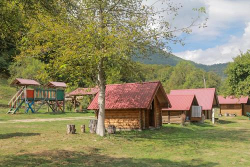 ein Blockhaus mit einem Baum und einem Spielplatz in der Unterkunft Camp &Apartmens Scepanovic in Mojkovac