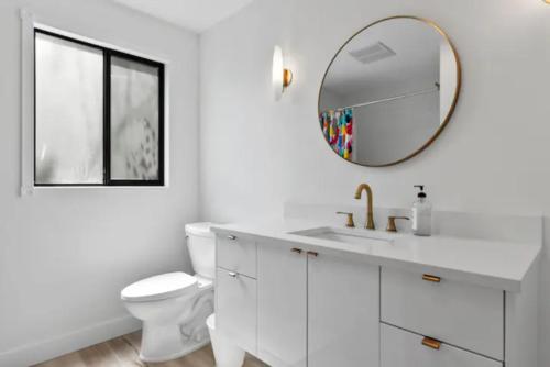 Baño blanco con lavabo y espejo en Mid-Century Modern Dream Retreat en West Kelowna