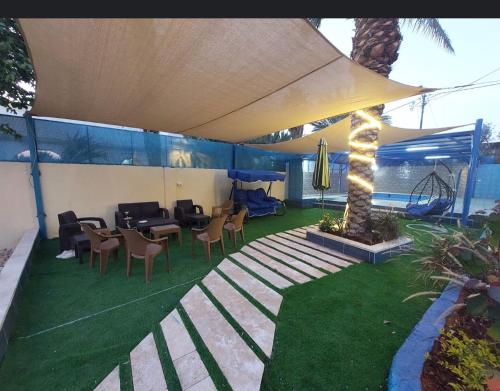 eine Terrasse mit einem Tisch, Stühlen und einem Sonnenschirm in der Unterkunft شاليه الهيبة alhaybeh chalet in Amman