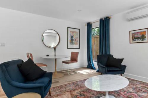 a living room with two chairs and a table and a mirror at Mid-Century Modern Dream Retreat in West Kelowna
