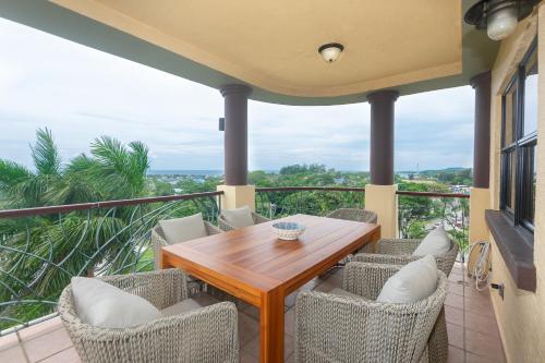 a balcony with a wooden table and chairs at Pineapple Villa 142 condo in Roatan
