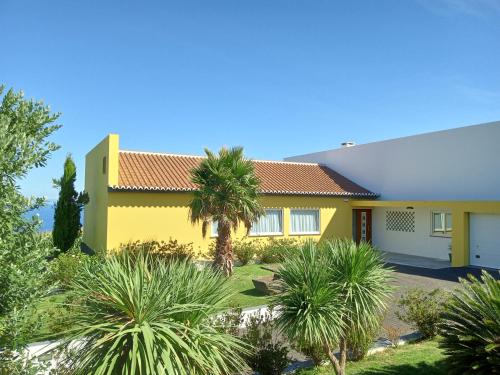 una casa amarilla con palmeras delante en Four Winds House, en Altares