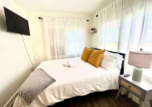una camera da letto con un letto con lenzuola bianche e cuscini gialli di Cozy 2 Bedroom Apartment Near Local Hotspots a West Palm Beach