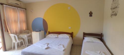 a bedroom with two beds and a yellow wall at Suítes Jardim dos Sonhos in Ubatuba