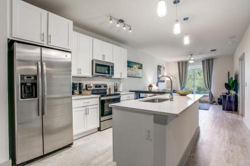 a kitchen with white cabinets and a stainless steel refrigerator at Luxury Condo facing RiverWalk Free Parking Pet Friendly Centrally Located in San Antonio