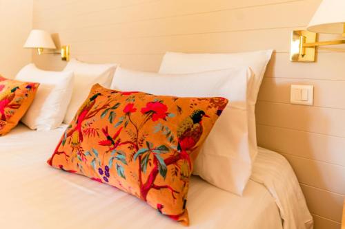 a bed with white pillows and an orange pillow at Le Mas de La Crémaillère in Gréoux-les-Bains