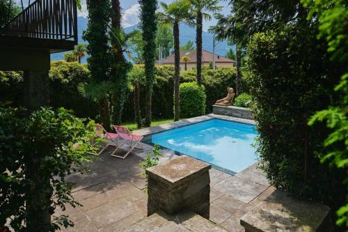 a swimming pool in a yard with a pink chair at Casa Navegna in Minusio