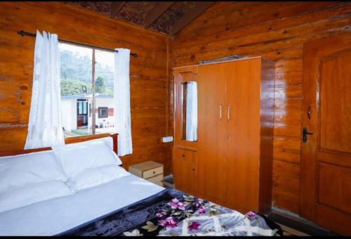 um quarto com uma cama branca e uma janela em Sandy Wood House Ooty - 2Bhk Villa em Ooty
