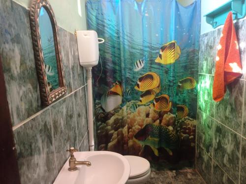 uma casa de banho com uma cortina de chuveiro temática de aquário e um lavatório. em MERMAID HOUSE, casa charmoso, wifi, parking, jardim, cozinha, central CANOA QUEBRADA em Aracati