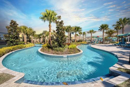 a swimming pool at a resort with palm trees at The Happy Place! - Upgraded Fun Windsor Home in Kissimmee