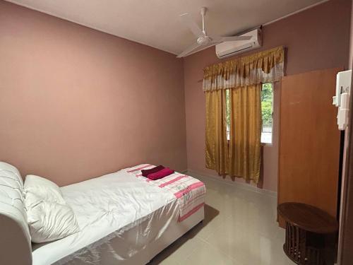 a bedroom with a bed and a window with a fan at Homestay Taman Hidayah Chawas in Tanah Merah