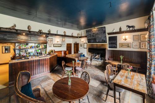restauracja ze stołami i krzesłami oraz bar w obiekcie The Blue Lion w mieście East Witton