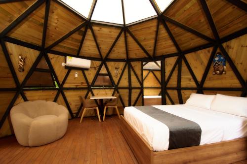 a bedroom in a room with a bed and a chair at HOTEL KOKUMI in Rionegro