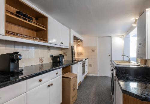 a kitchen with white cabinets and a black counter top at Quality Stay Room in Brighton & Hove