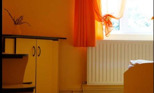 uma cozinha com uma cortina laranja e uma janela em Kristóf kulcsosház em Gheorgheni
