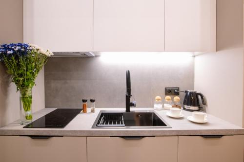 a kitchen with a sink and a vase of flowers at hotelise l illusion Apartment in Yerevan