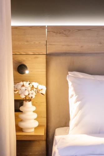 a vase of flowers on a table next to a bed at hotelise l illusion Apartment in Yerevan