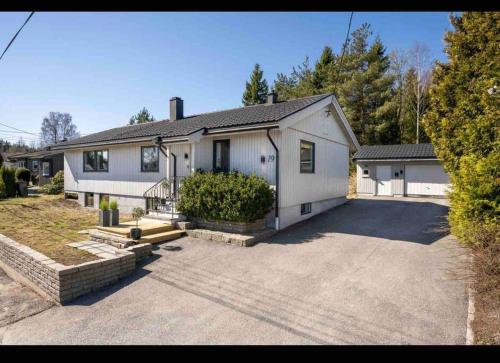 a large white house with a driveway at Nyoppusset og romslig leilighet med 6 soveplasser i et familievennlig område in Sarpsborg