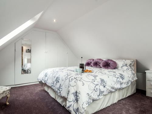 um quarto branco com uma cama grande e almofadas roxas em Silver Birch Lodge em Horsley